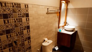 Un baño con inodoro, lavamanos y azulejos estampados.