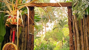 Un arco de madera que da acceso a un jardín con escalones y una silla de mimbre.