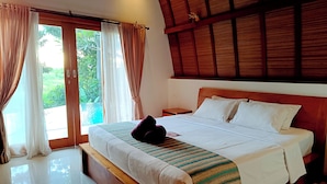 Habitación de hotel con una cama grande, cabecero de madera y vista a una piscina.