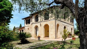 A two-story stone building with arched doorways and a balcony. - Villa with panoramic pool (Castorano)