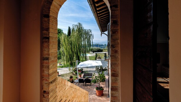 An arched doorway leading to an outdoor patio with a table, chairs, and potted plants. - Villa with panoramic pool (Castorano)
