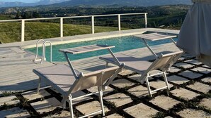A pool area with two lounge chairs and a covered umbrella, overlooking a mountainous landscape. - Villa with panoramic pool (Castorano)