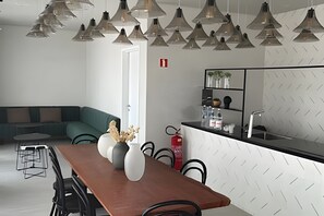 A modern kitchen with a black countertop, white patterned backsplash, and a dining area with a wooden table and chairs. - Studio Próximo a Paulista (São Paulo)