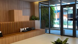 Een moderne receptie met een houten bank, een plant in pot en een glazen deur naar buiten.