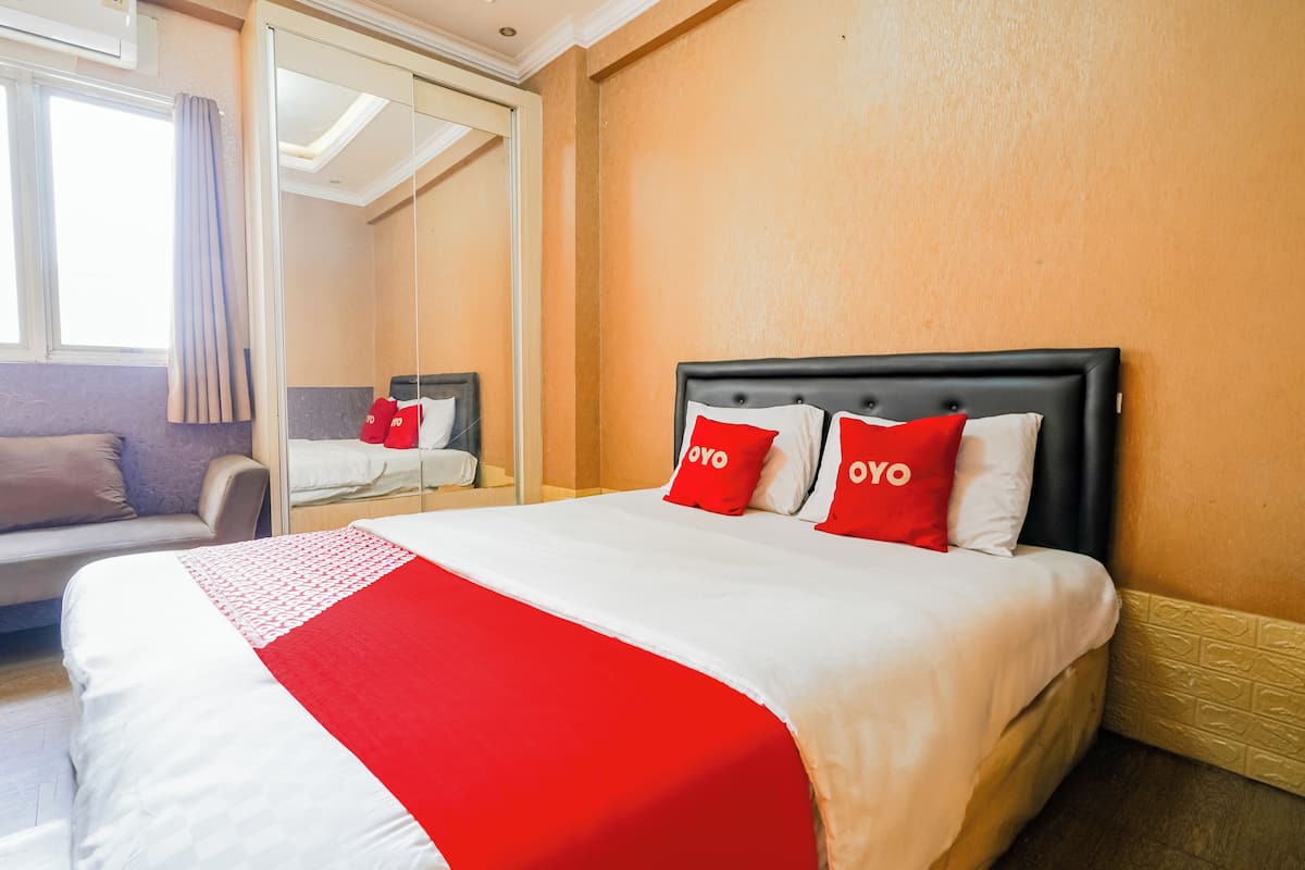 Habitación de hotel con una cama grande, un sofá y un espejo.