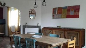 Zona pranzo con tavolo e sedie in legno, camino e opera d'arte moderna appesa al muro.
