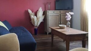 Un soggiorno con una parete rossa, un tavolino in legno, un divano e una televisione su un mobile.