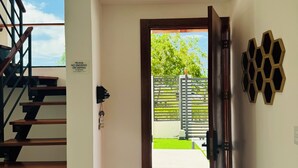 Un intérieur moderne avec un escalier, une porte donnant sur l’extérieur et un élément décoratif hexagonal fixé au mur.