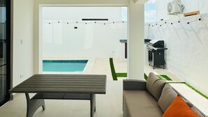 Un espace de vie extérieur moderne comprenant une piscine, une table à manger et un canapé.
