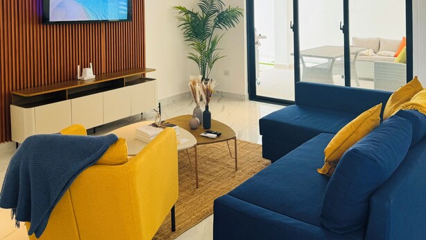 Un salon moderne comprenant un téléviseur à écran plat, un canapé, une table basse et un coin repas.