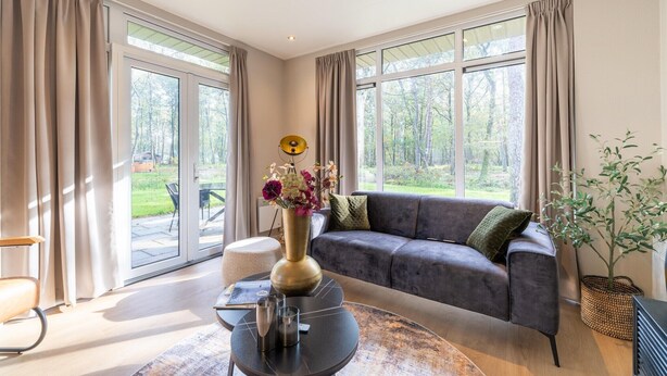 A modern living room with a grey sofa, a round coffee table, and a vase with flowers. - Vacation Home in Haarle near Hellendoorn (Haarle)