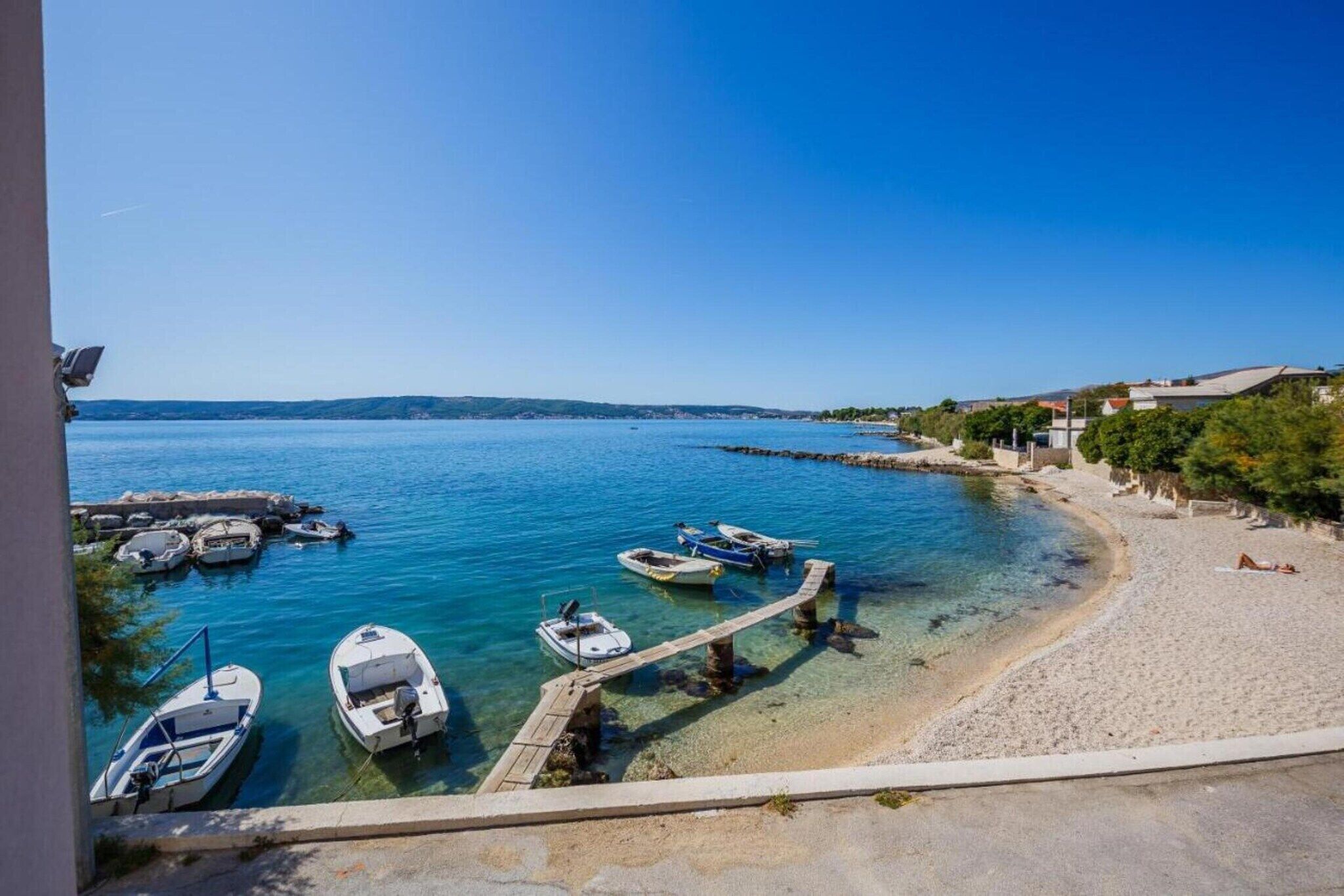 A coastal view with boats docked near a sandy beach and a clear blue sky.
