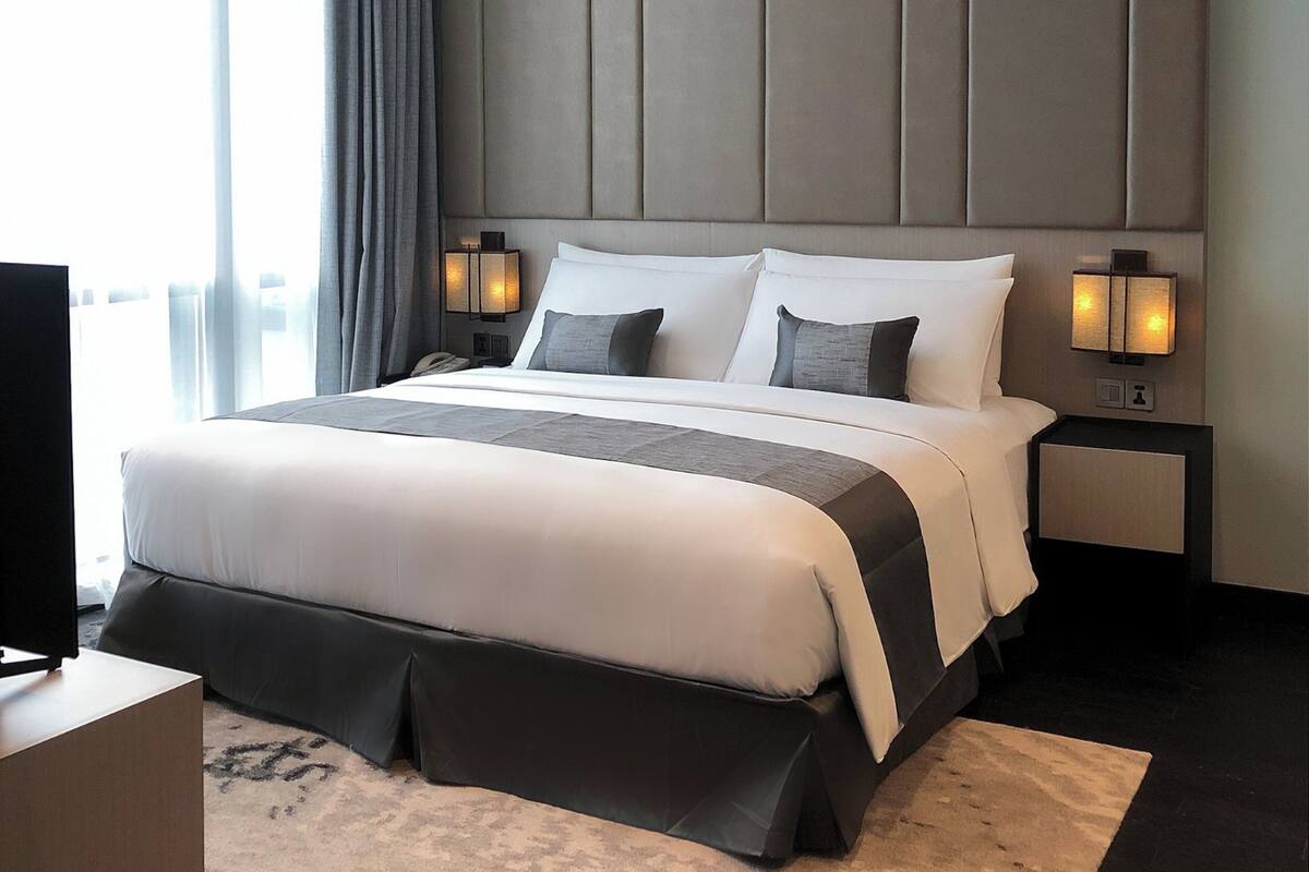 Habitación de hotel moderna con una cama grande, un televisor de pantalla plana y vistas a la ciudad.