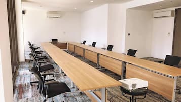 Ein Konferenzraum mit einem langen Tisch, Stühlen und einem Projektor.