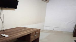 A room with a wooden desk, a flat-screen TV mounted on the wall, and a tiled floor. - OYO 93948 Bunda Rachma Rooms (Depok)