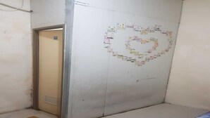 A room with a door, a wall decorated with a heart-shaped collage, a yellow mat on the floor, and a blue object on the right. - OYO 93948 Bunda Rachma Rooms (Depok)