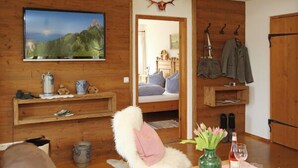 Um quarto aconchegante com paredes de madeira, televisão montada, lareira e cama com vista para as montanhas.