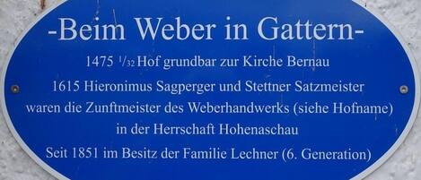 Eine historische Gedenktafel mit Text in deutscher Sprache, an einer weißen Wand angebracht.