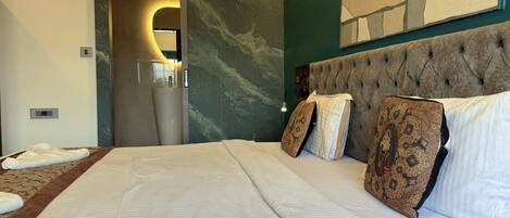 Habitación de hotel con una cama grande, pared de mármol, baño moderno y una obra de arte de gran tamaño en la pared.