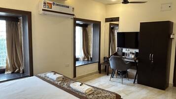 Una habitación de hotel con cama, escritorio, silla, armario y ventilador de techo.
