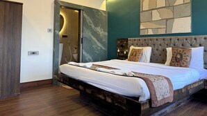 A modern bedroom with a large bed, a wooden headboard, and a stone accent wall. - The Aster Heritage (Kolkata)