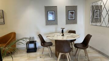 Un comedor con una mesa redonda, seis sillas e imágenes enmarcadas en la pared.
