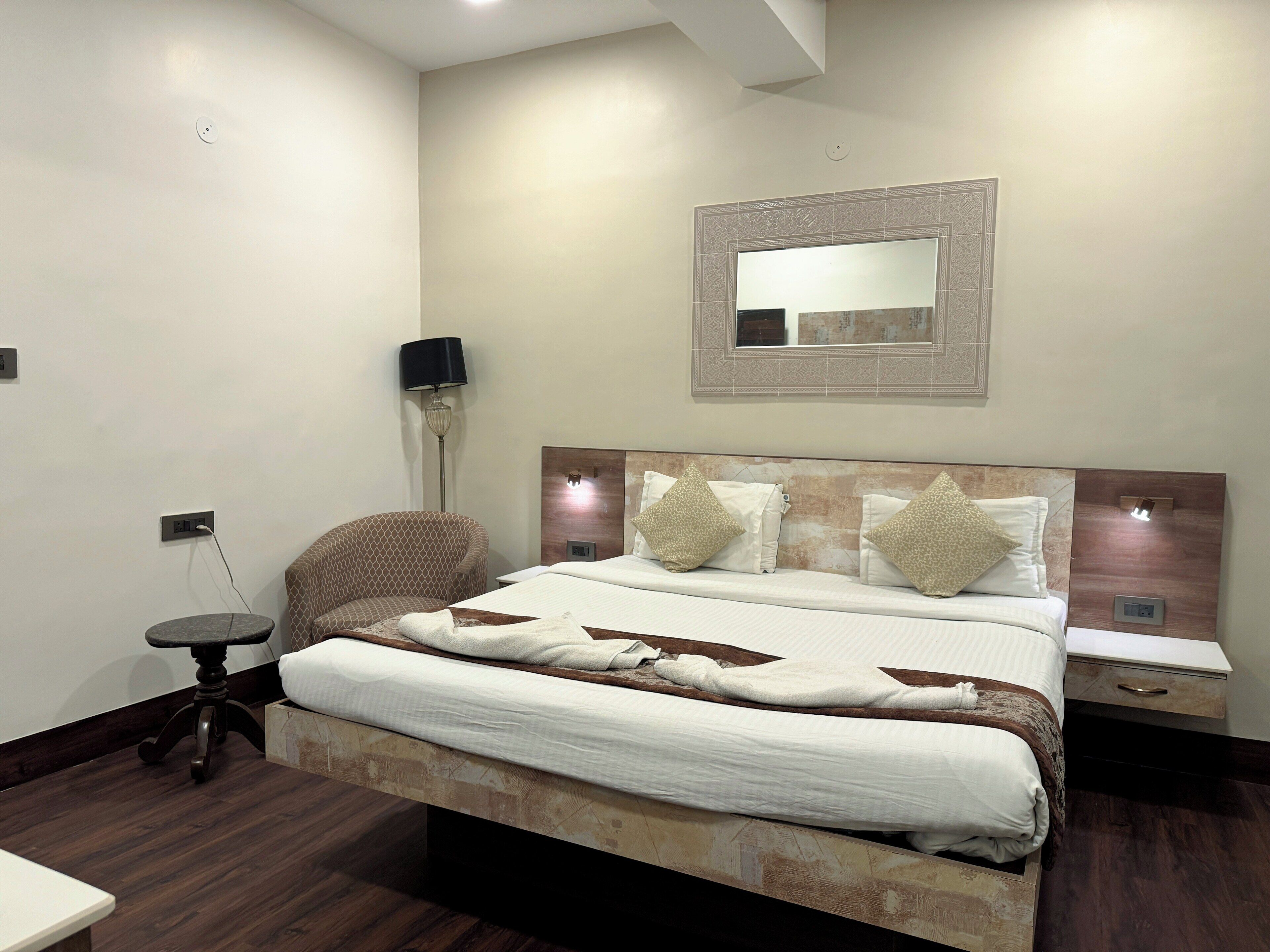 A neatly arranged bedroom with a large bed, bedside tables, a chair, and a lamp.