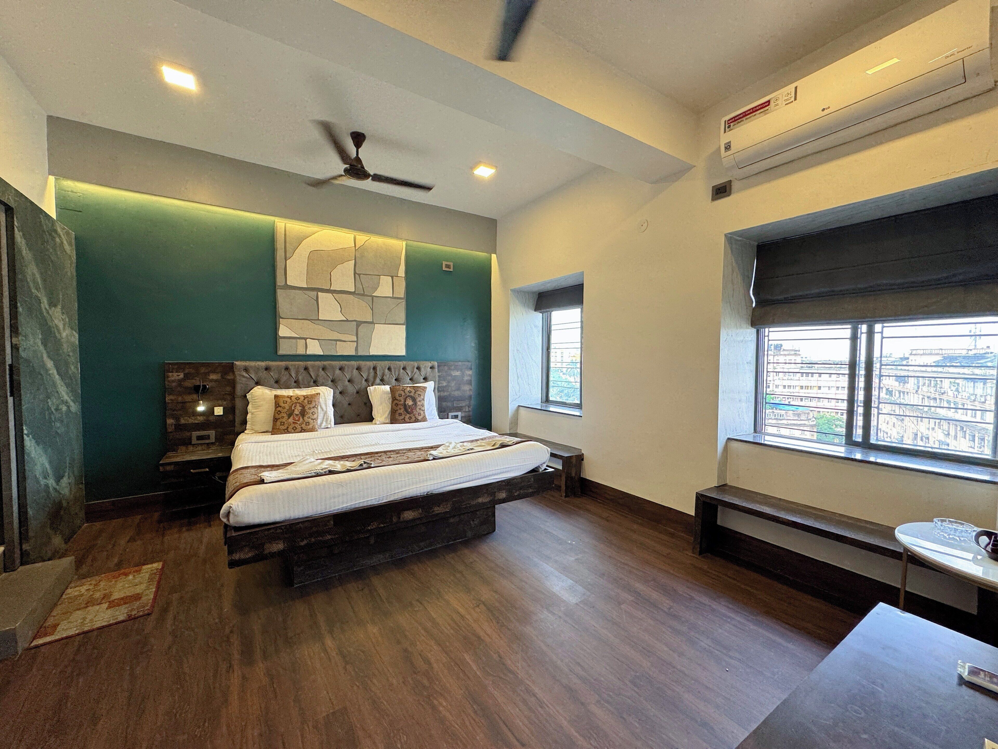 A modern bedroom with a large bed, a ceiling fan, and a window with a city view.