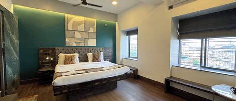 A modern bedroom with a large bed, a ceiling fan, and a window with a city view.