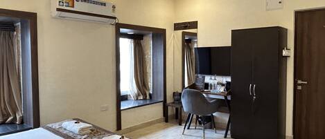 Una habitación de hotel con cama, escritorio, armario y ventilador de techo.