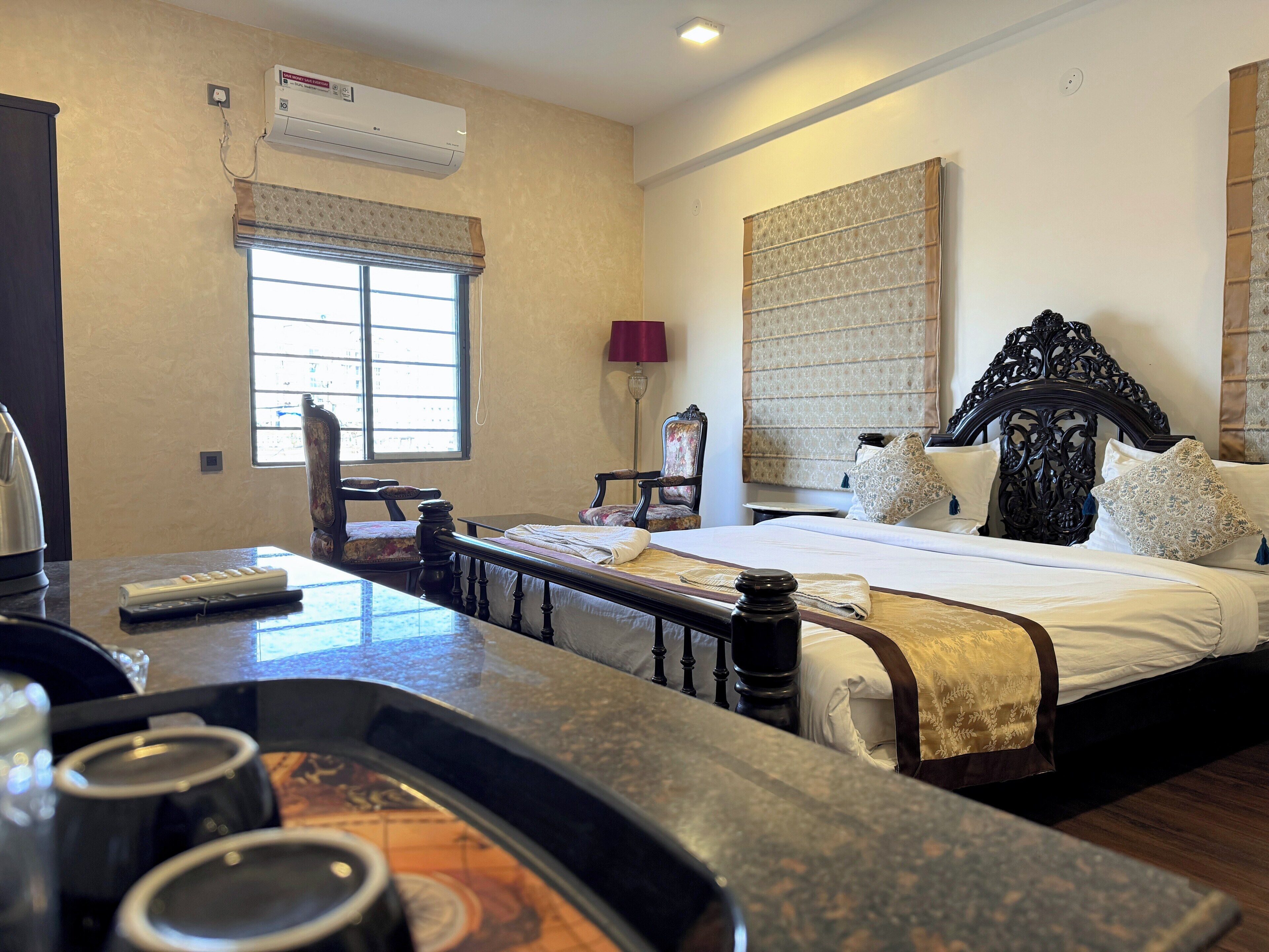 Una habitación de hotel con cama, una silla, una mesa con control remoto y una ventana.
