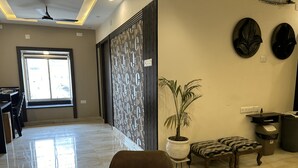 A modern hotel lobby with a marble reception desk, a potted plant, a seating area with patterned cushions, and a large window providing natural light. - The Aster Heritage (Kolkata)