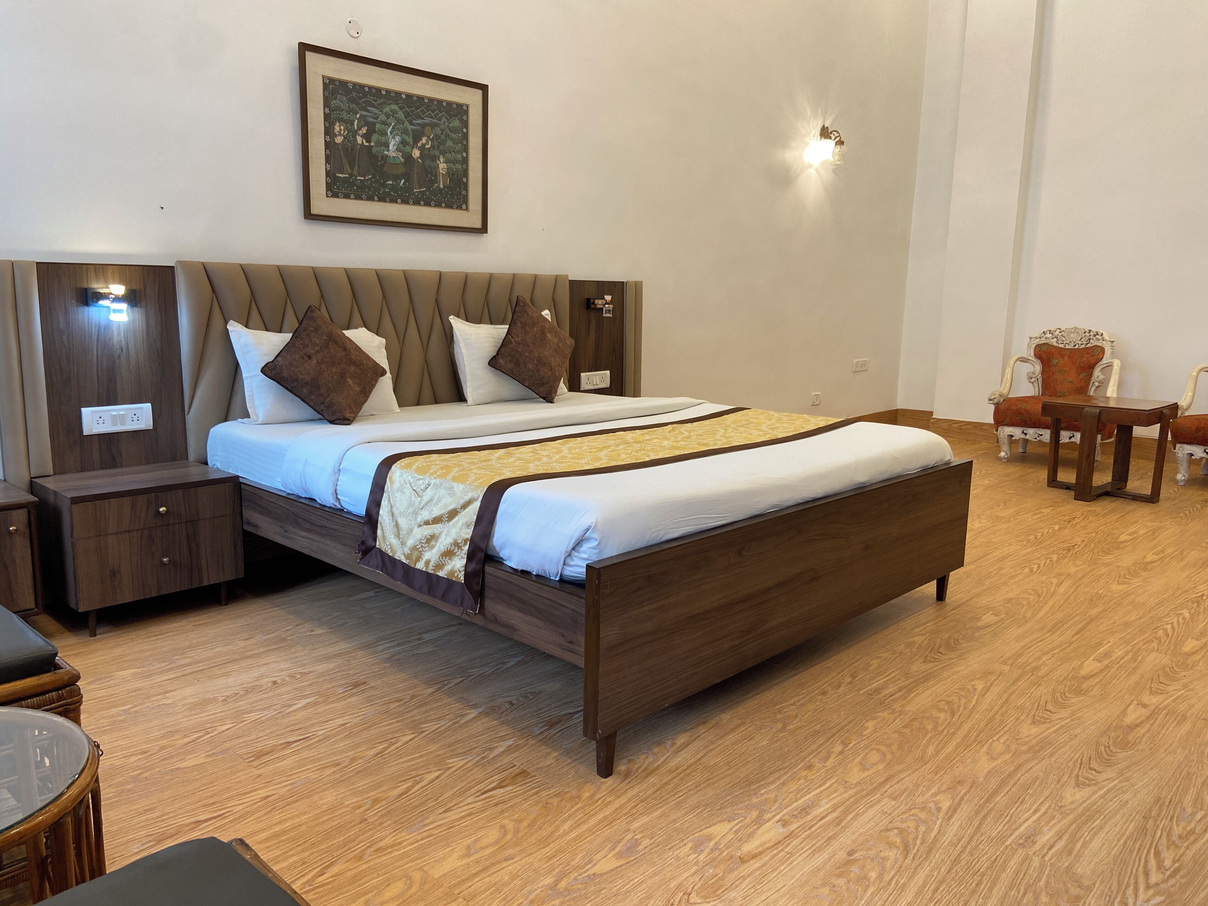 Un dormitorio ordenado con una cama grande, mesitas de noche, una silla y una pequeña mesa.