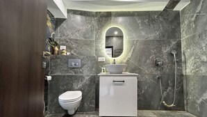 A modern bathroom with a marble floor, a white sink, a toilet, and a shower. - The Aster Heritage (Kolkata)