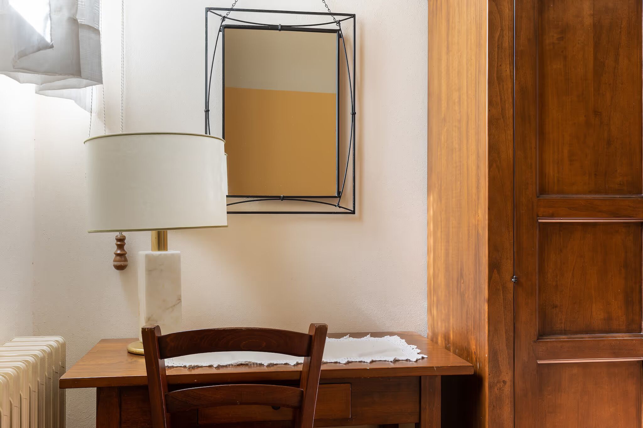 Une table en bois, une chaise, une lampe et un miroir encadré accroché au mur.