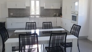 Una cocina moderna con armarios blancos, un comedor negro y cuatro sillas negras.
