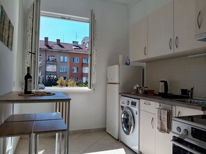Cocina compacta con lavadora, refrigerador y ventana con cortinas.