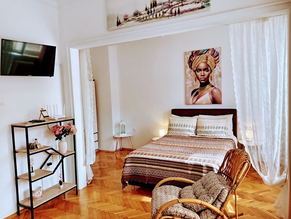 Une chambre à coucher comprenant un lit, un téléviseur, une console et une chaise.