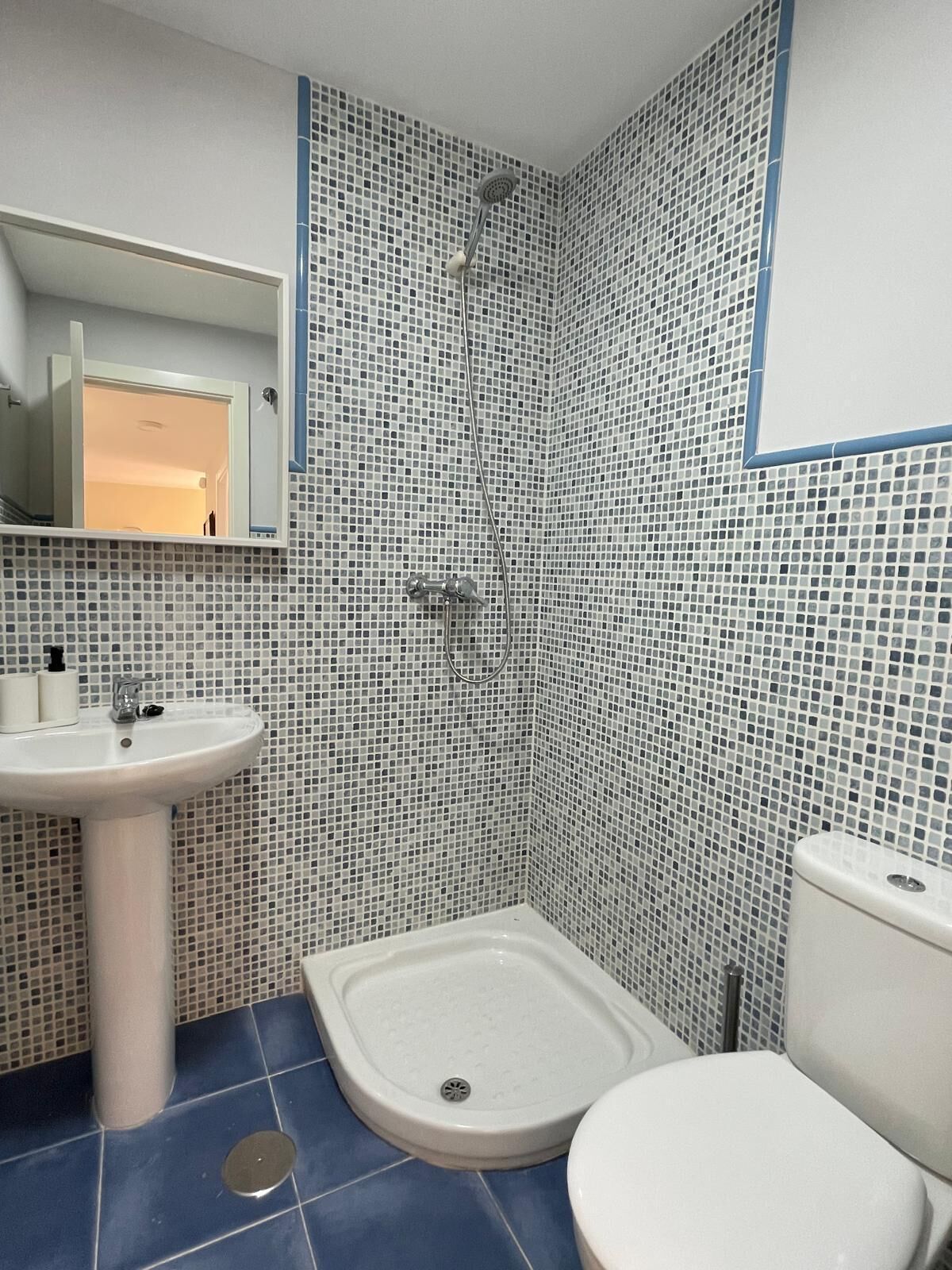 Un baño con lavamanos blanco, ducha e inodoro.
