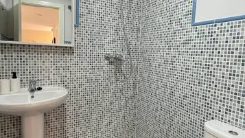 Un baño con lavamanos blanco, ducha e inodoro.