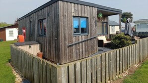 Une petite cabane en bois avec une véranda, une boîte aux lettres et une plante en pot.