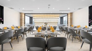 A modern dining area with tables set for four, arranged in rows, and a large window in the background. - Thai Ha Boutique Hotel (Bai Chay)
