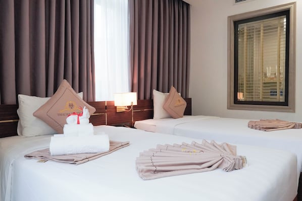 A hotel room with two beds, each with a pillow and a folded towel.