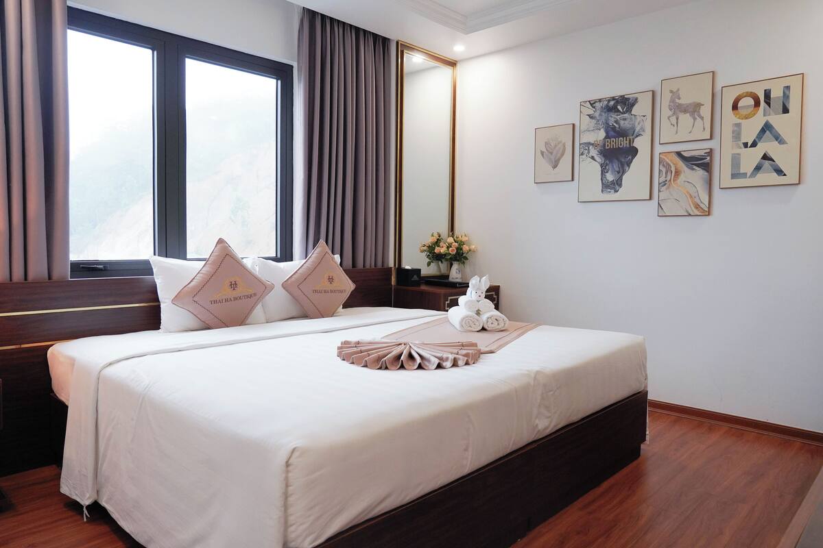 A hotel room with a large bed, a nightstand, a mirror, and artwork on the wall.