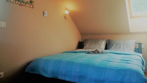 A bedroom with a bed, a wall-mounted light, and a wall decoration.