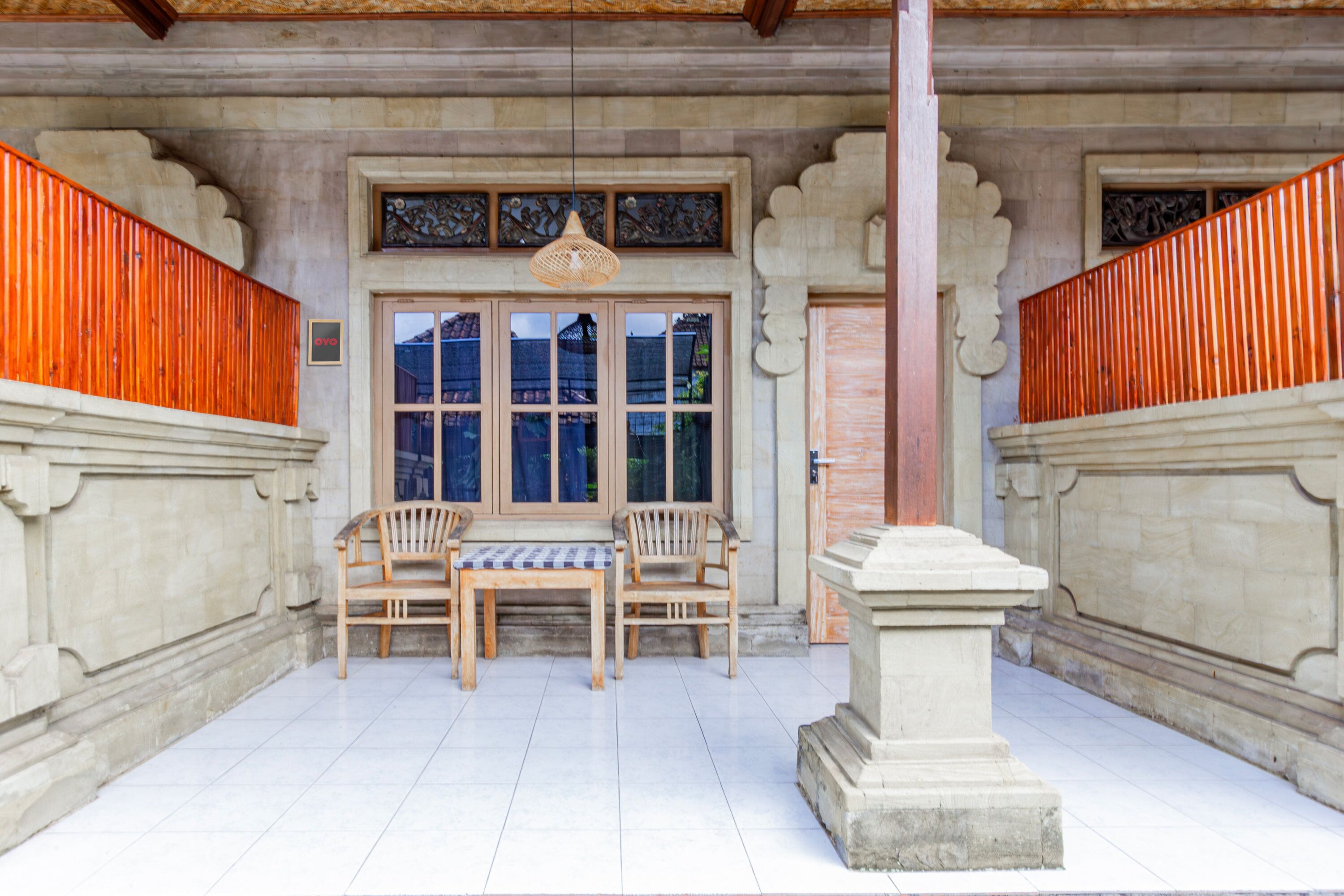 A traditional building entrance with a tiled floor, two wooden benches, a table, and a stone pedestal.