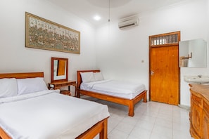 A hotel room with two wooden beds, a large decorative wall hanging, a wooden wardrobe, a mirror, and a bathroom with a sink. - Belvilla Ratna Resort Ubud PalaceNearUbud Palace (Ubud)