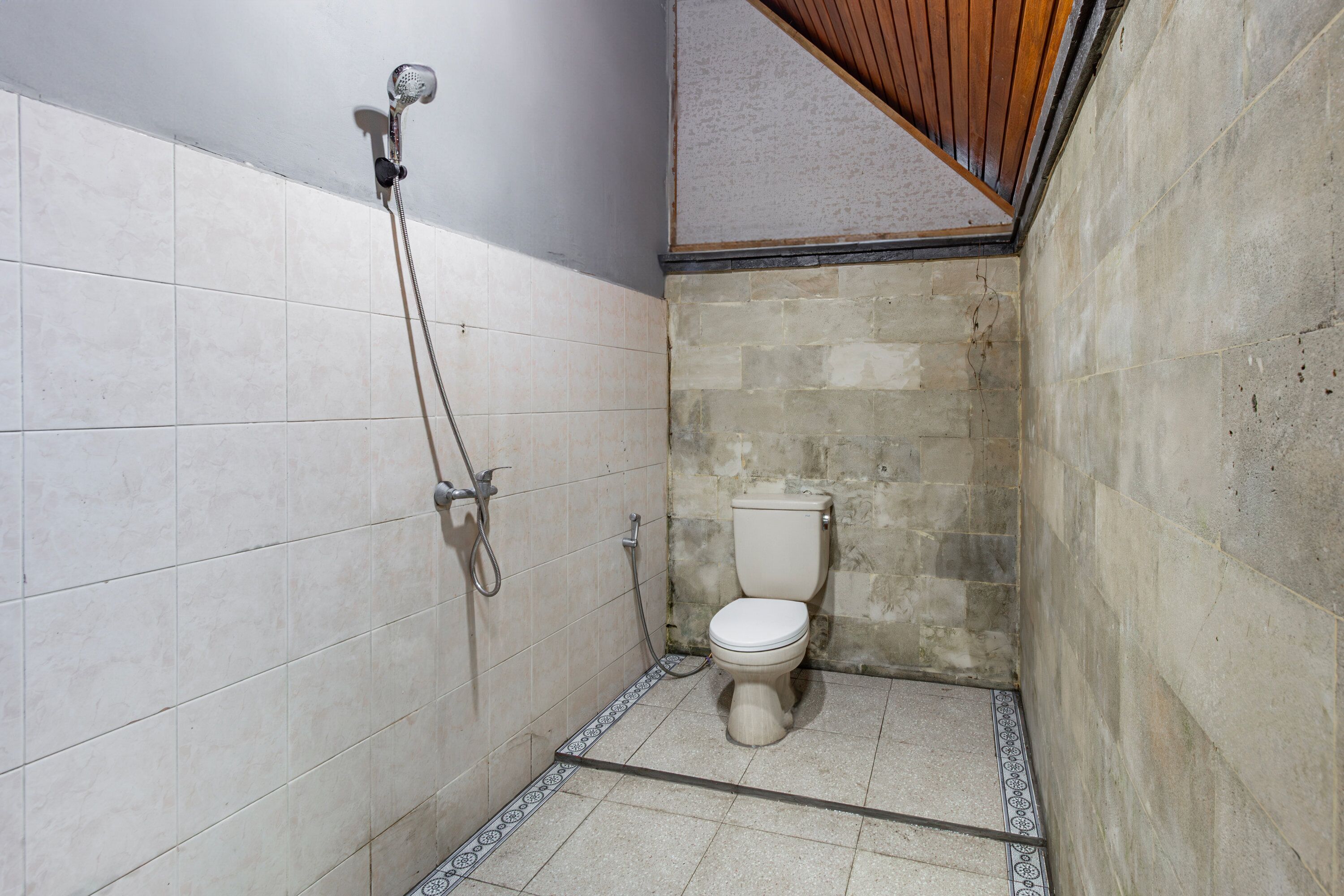 A small, narrow bathroom with white tiled walls and a toilet.