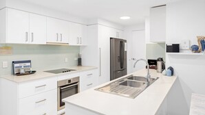 A modern kitchen with white cabinetry, stainless steel appliances, and a built-in sink. - Sounds of the Ocean on Boyd (WOORIM)