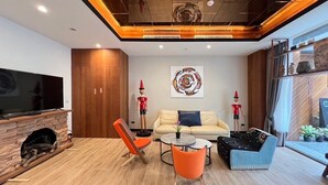 A modern living room with a fireplace, a flat-screen TV, a sofa, a coffee table, and two chairs. - Sun lake Hotel (Yuchi)